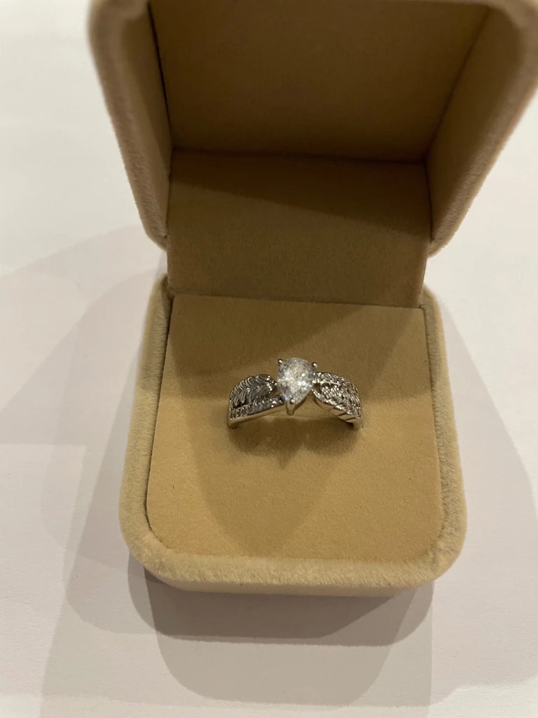 Bague de couleur argentée avec pierre centrale transparente et motifs feuillage scintillants