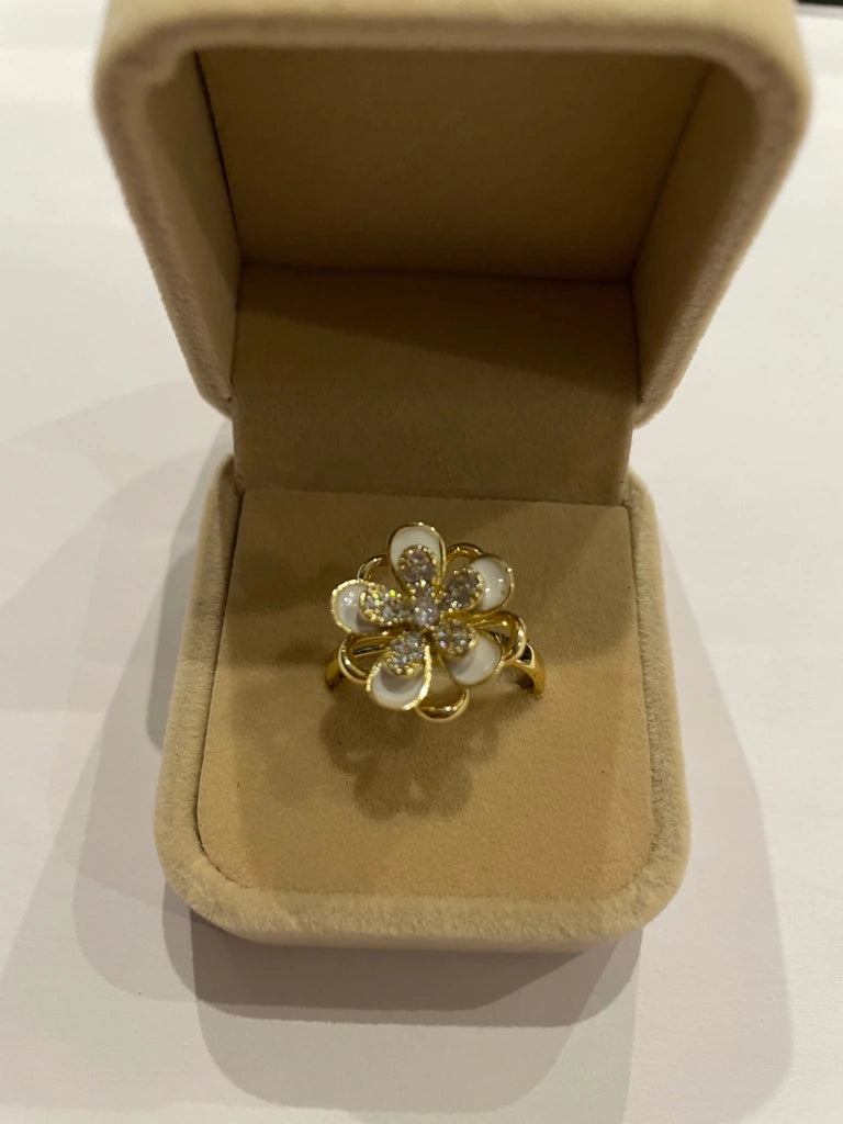 Bague dorée ornée d’une fleur blanche aux détails transparents et scintillants