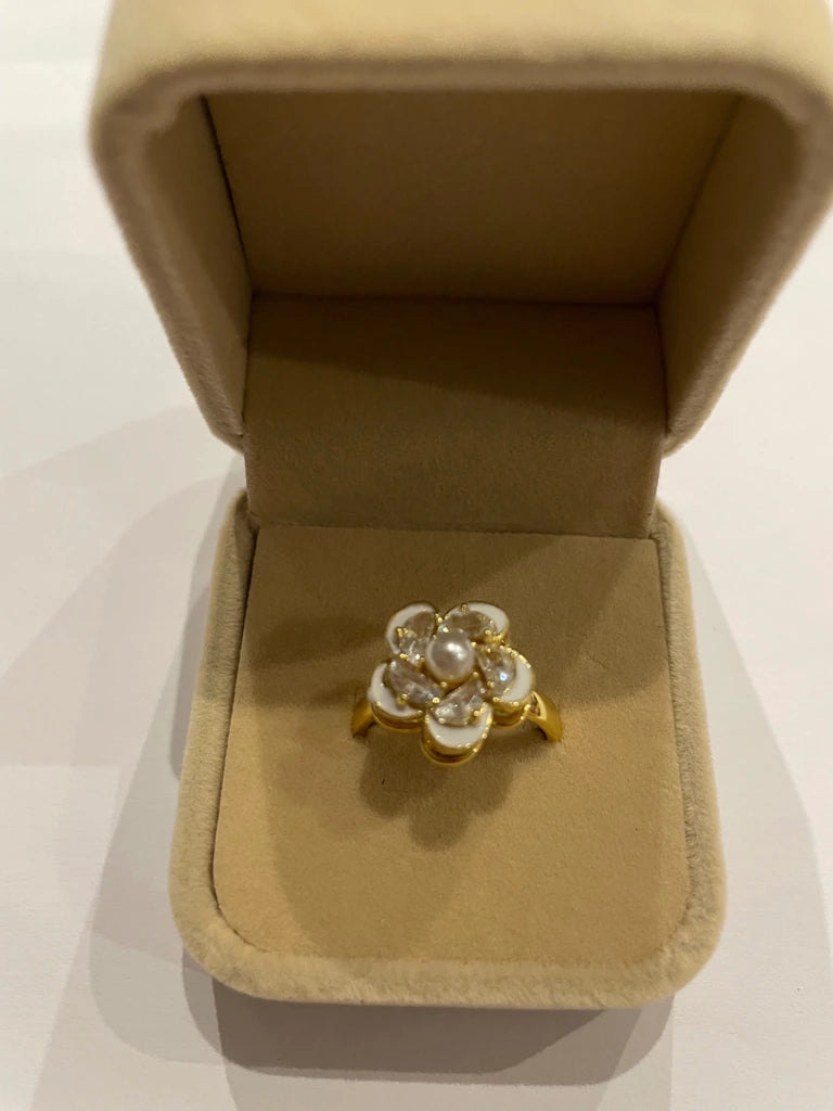 Bague de couleur dorée ornée d’une fleur blanche en relief avec centre à l’aspect perlé