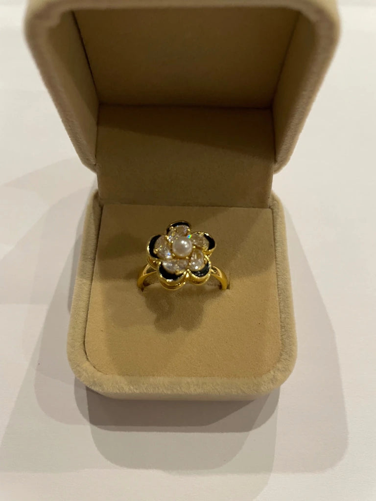 Bague dorée en forme de fleur avec pétales transparents, touches noires et centre à l’effet