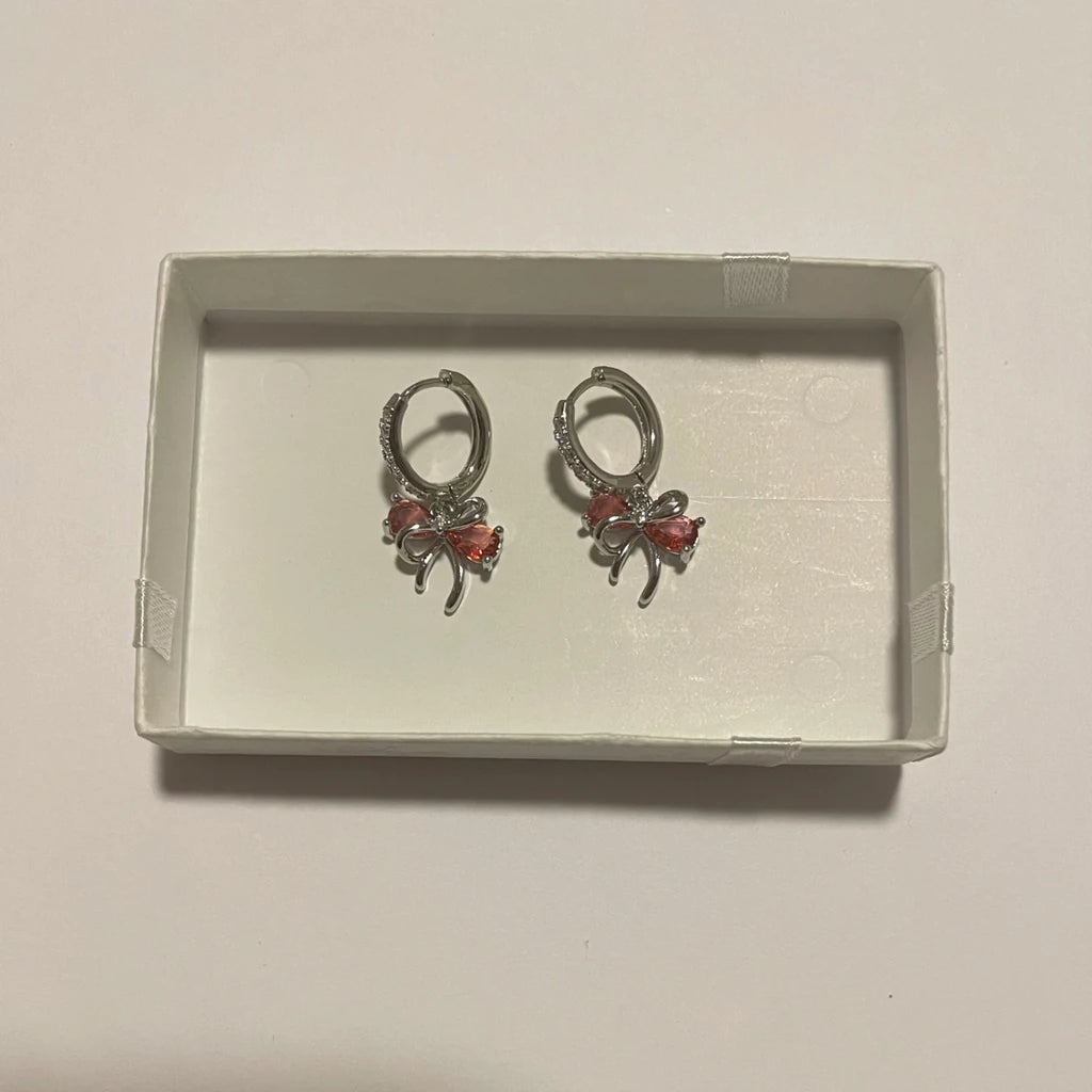 Paire de créoles de couleur argentée avec nœuds pendants ornés de détails rose corail