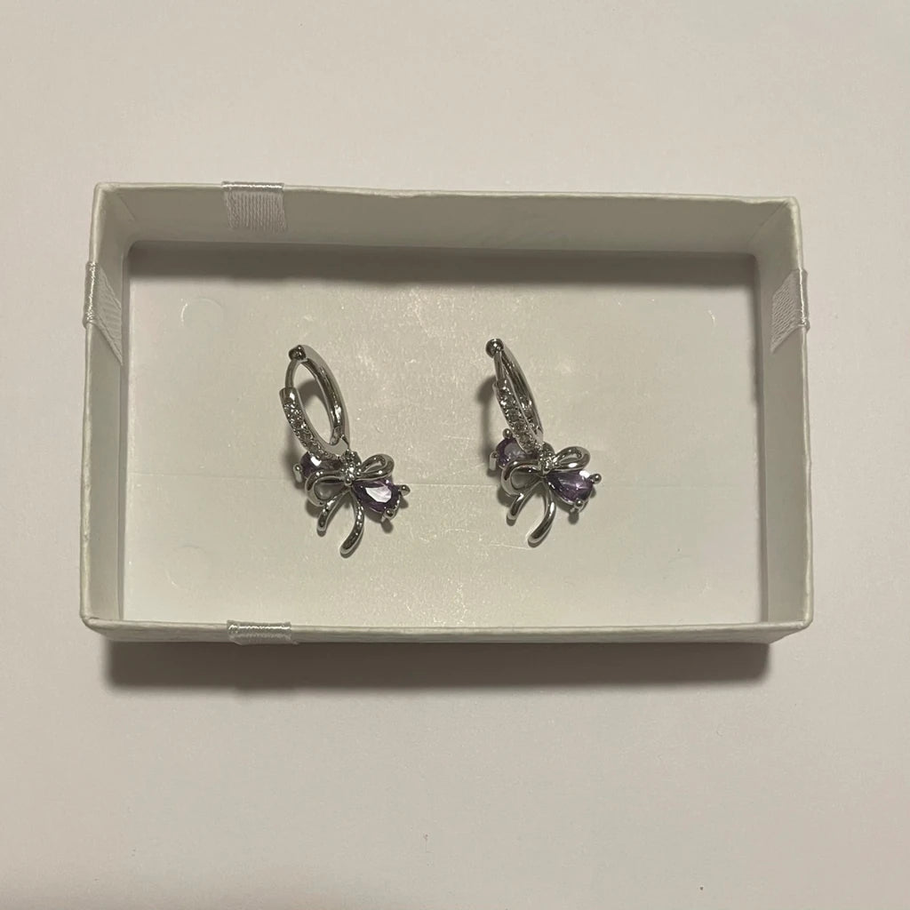 Paire de créoles de couleur argentée avec nœuds pendants ornés de détails violets