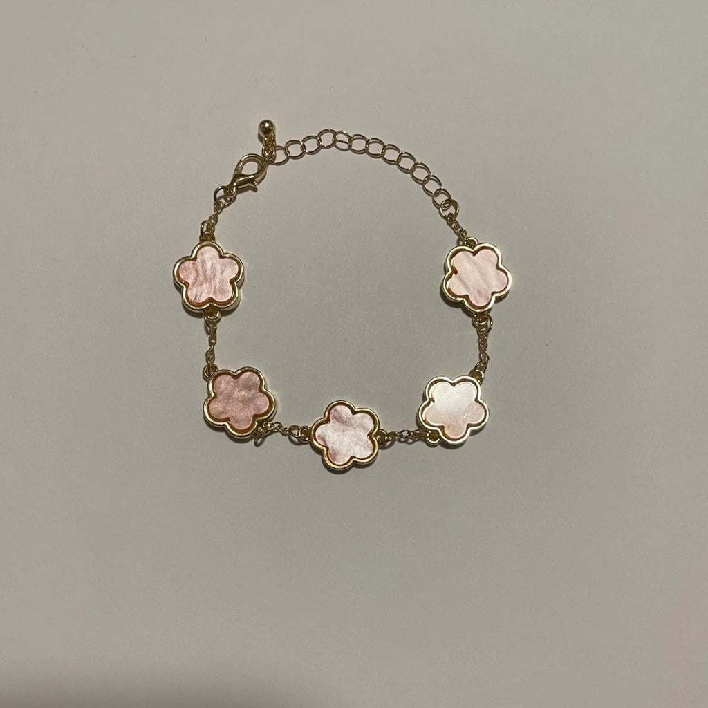 Bracelet doré à cinq fleurs roses effet nacré, avec fermoir mousqueton et chaînette de rallonge