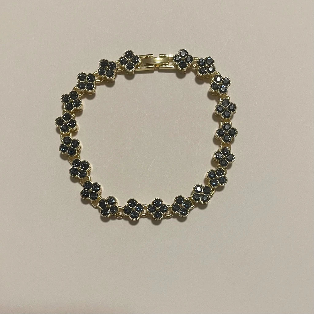 Bracelet de couleur dorée composé de motifs trèfle à quatre pétales ornés de détails foncés scintillants