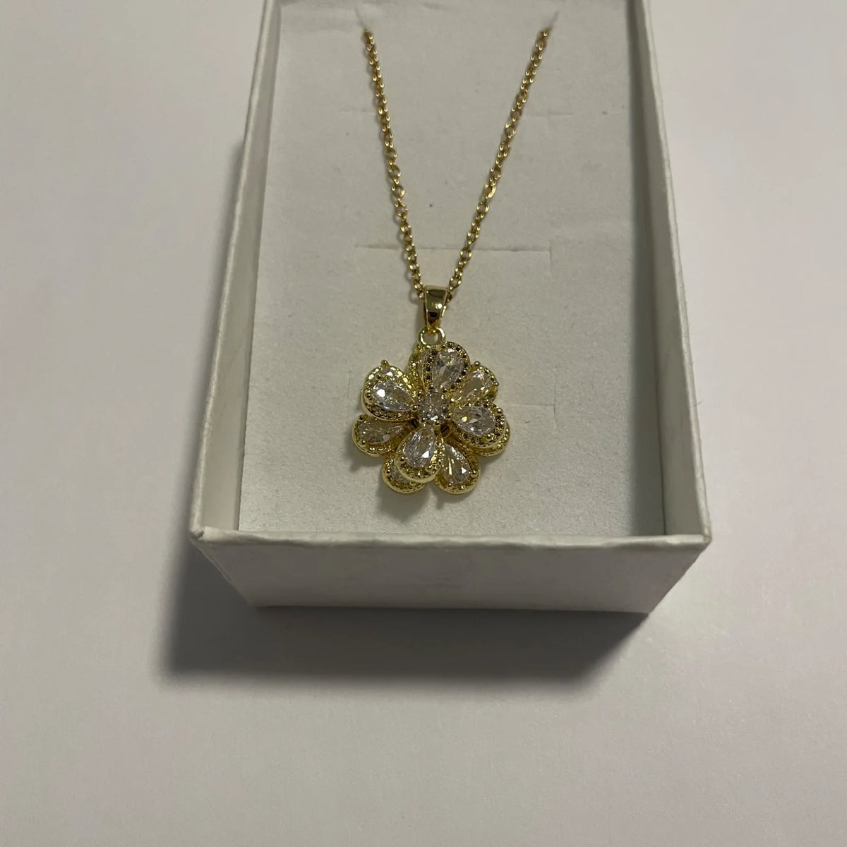 Collier fleur doré avec pendentif tournant et pétales transparents facettés