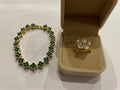 Bracelet doré à motifs trèfle vert et bague dorée à fleur blanche, présentés dans deux écrins