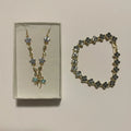 Collier doré à fleurs bleues et nœud turquoise, accompagné d’un bracelet à motifs trèfle foncés