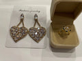 Parure dorée composée d’une bague fleur et de grandes boucles d’oreilles cœur scintillantes