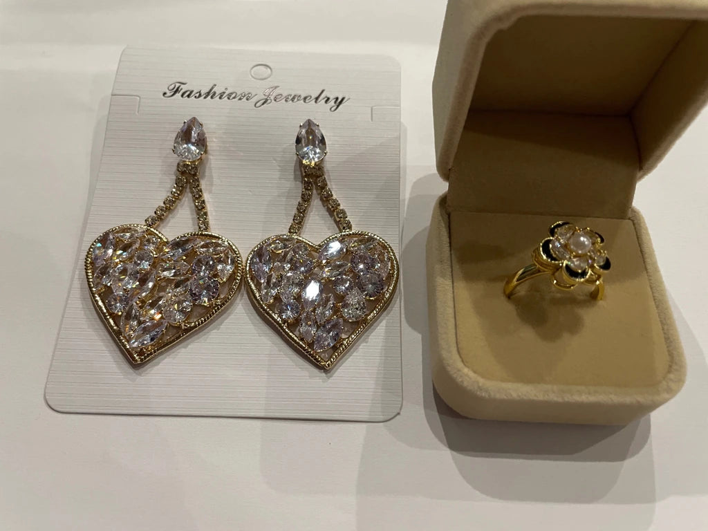 Parure dorée composée d’une bague fleur et de grandes boucles d’oreilles cœur scintillantes