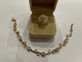 Parure dorée composée d’une bague rose blanche et d’un bracelet feuillage scintillant
