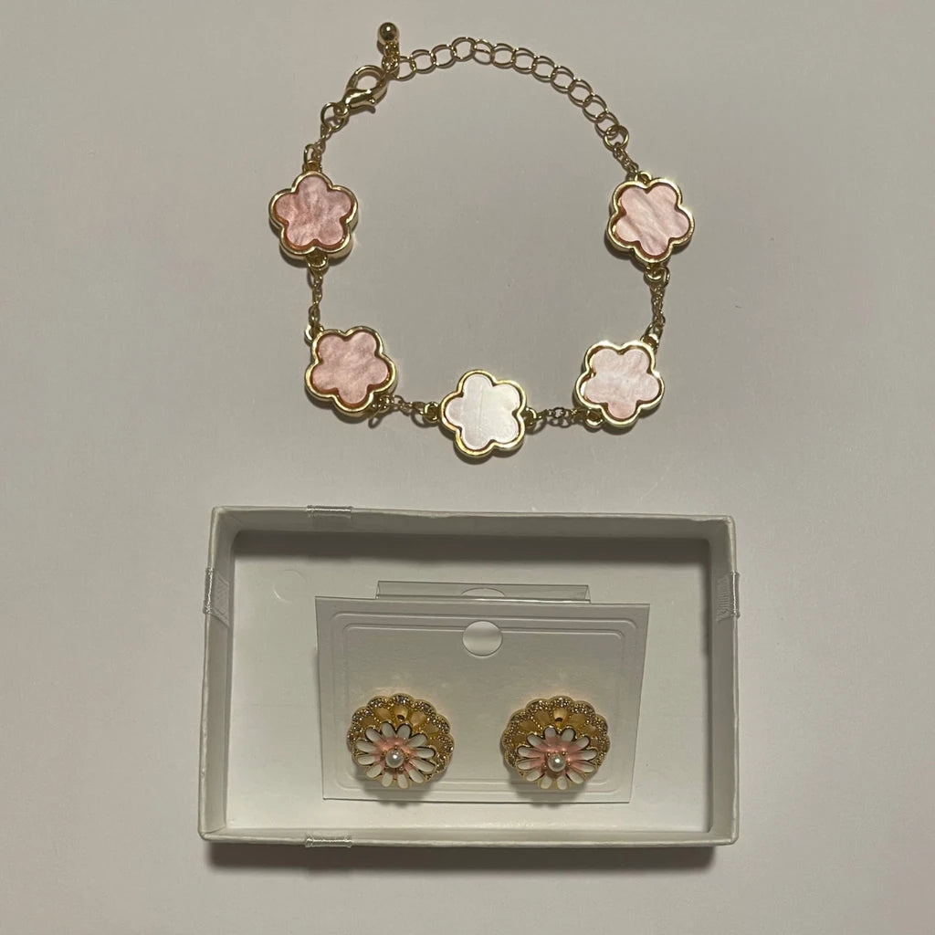Bracelet doré à cinq fleurs roses et boucles d’oreilles florales roses et blanches présentées dans un écrin clair