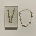 Collier et bracelet assortis de couleur dorée, ornés de fleurs violettes, de feuilles et de nœuds