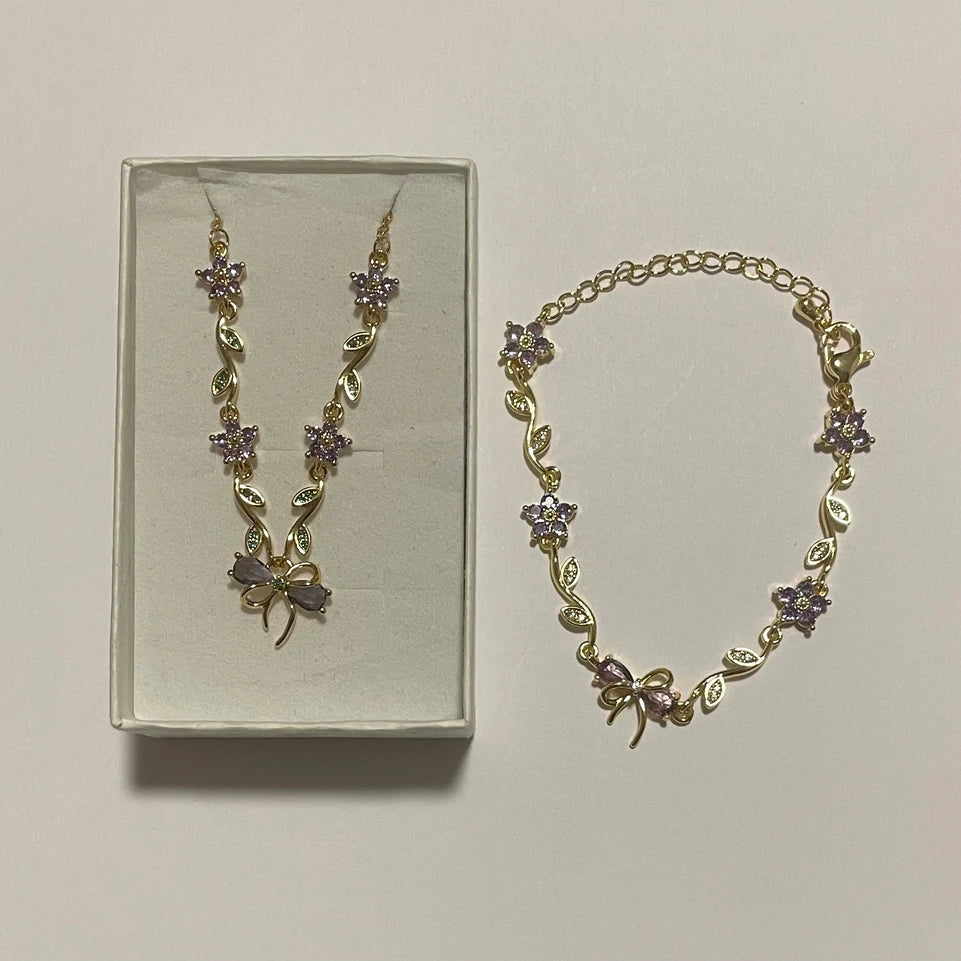 Collier et bracelet assortis de couleur dorée, ornés de fleurs violettes, de feuilles et de nœuds